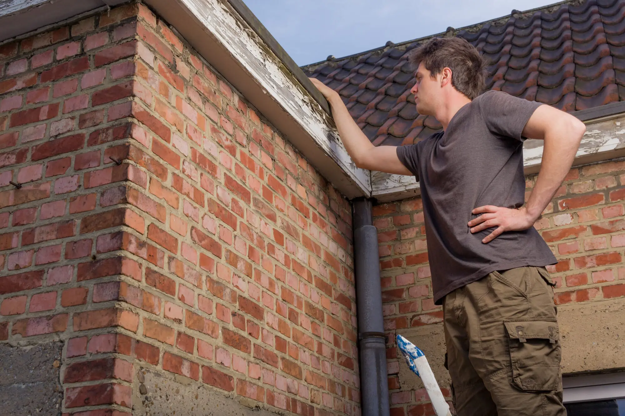 man inspecting the roof of an old house