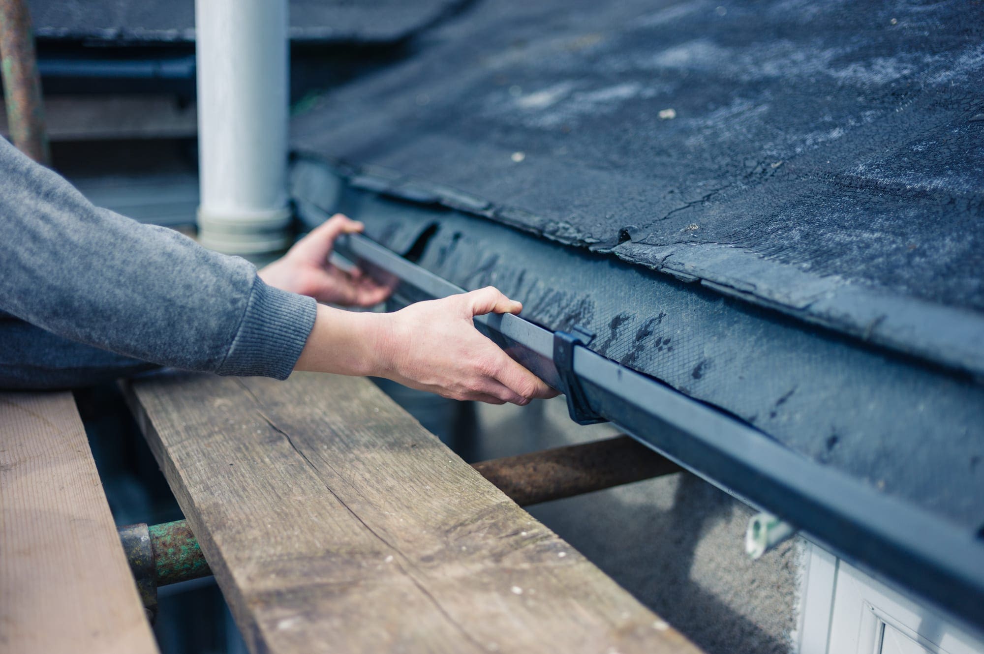 hands of a worker fixing roof gutter